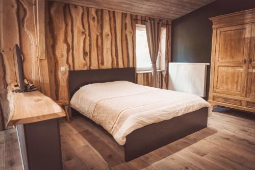 a bedroom with a bed and a wooden wall at Oh la vache in Stoumont