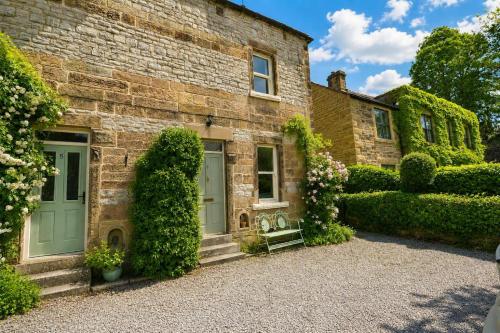 a brick house with a door and ivy at Brookfield Cottages in Bakewell