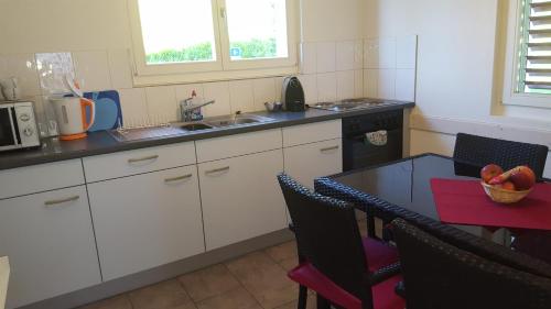 a kitchen with white cabinets and a table with a bowl of fruit at Ferienwohnung Suter in Seewen