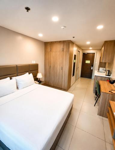 a bedroom with a large white bed and a kitchen at Milton Hotel Makati in Manila