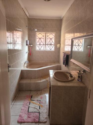 a bathroom with a sink and a tub and a mirror at The Corner Lounge - Lenasia in Lenasia