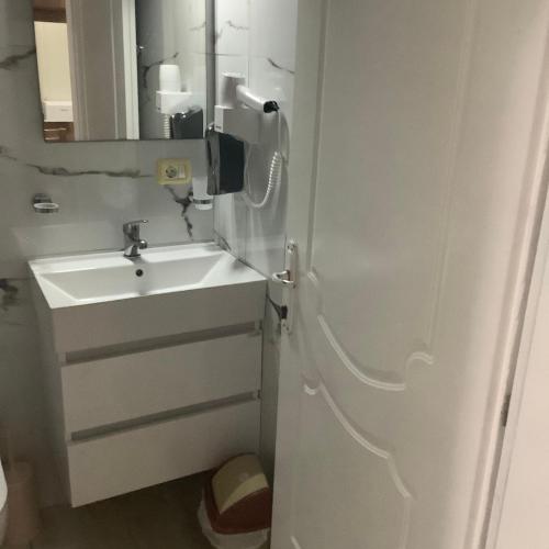 a white bathroom with a sink and a mirror at Erjani Hotel in Velipojë