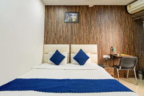 a bedroom with a bed with blue pillows and a desk at Hotel Gareen By Du Rooms Near Delhi University Kamlangar in New Delhi