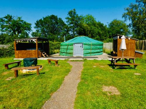 a camping area with a yurt and benches in a field at Glamp and Tipple Ltd in Great Ellingham