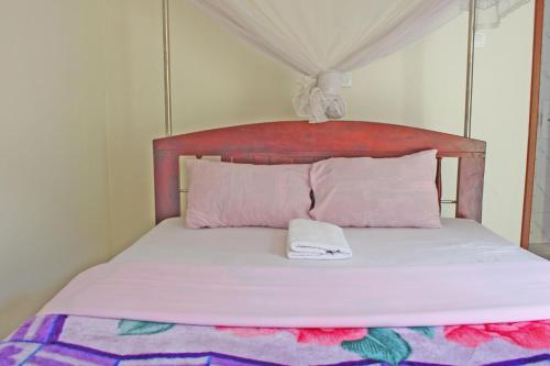 a bed with a wooden headboard with a towel on it at Kolstar Hotel SMC Ltd in Ogwam