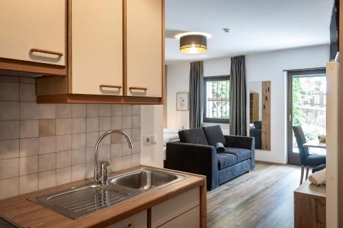 a kitchen with a sink and a living room at Aparthotel Feldhof Nature in Bolzano