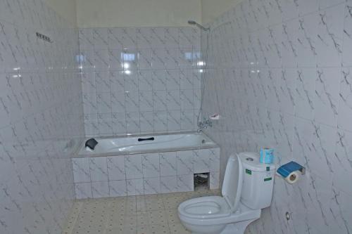 a white bathroom with a toilet and a tub at Kolstar Hotel SMC Ltd in Ogwam