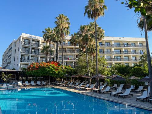 a hotel with a pool and chairs and palm trees at Veronica Hotel in Paphos
