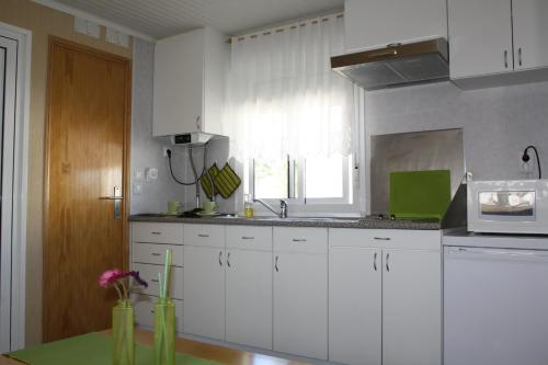 a kitchen with white cabinets and a sink and a window at Valbom by Campigir in Sesimbra
