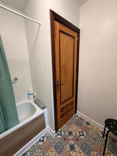 a bathroom with a tub and a wooden door at Casa Escalones in Villalba