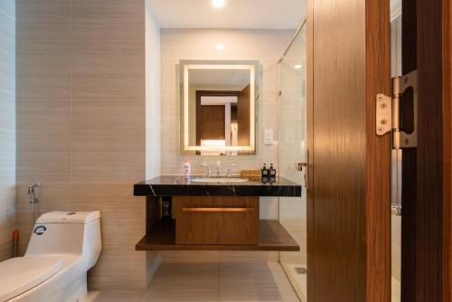 a bathroom with a sink and a mirror and a toilet at HD Panorama Nha Trang Condotel & Pool in Nha Trang