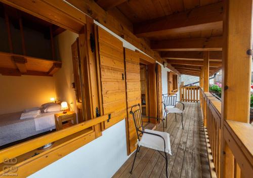 ein Zimmer mit Bett und Stühlen auf einer Holzterrasse in der Unterkunft Dependance GRIMANI in Ampezzo