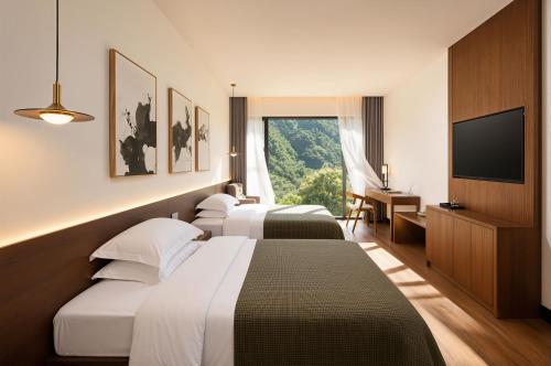 a hotel room with three beds and a flat screen tv at Zhangjiajie National Park Nvue Resort Free Laundry & Dry Service,Free Fresh coffee& Customizing Tour Plan in Zhangjiajie