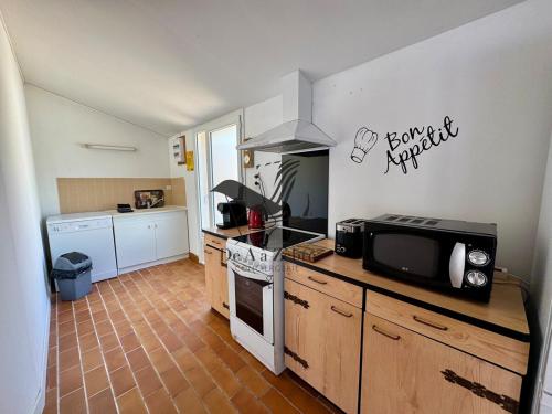 a kitchen with a stove and a microwave at L'Océane - Maison au calme avec terrasse, centre de Bourg in Le Port-des-Barques