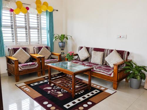 a living room with couches and a coffee table at Neartown Homestay in Kushālnagar
