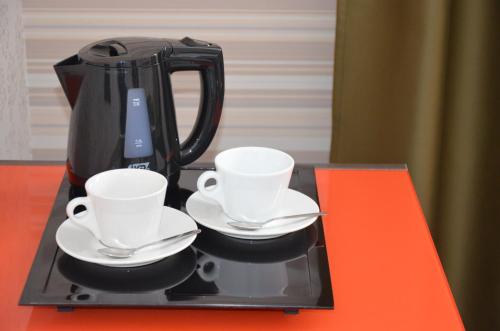a black coffee maker with two cups and saucers at Villa Four Rooms in Kharkiv