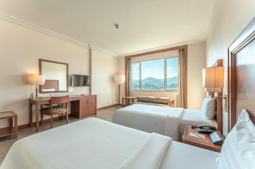 a hotel room with two beds and a desk at Grand Mandarin Betong Hotel in Betong