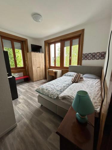a bedroom with a bed and a table and windows at La belle Époque in Tramelan