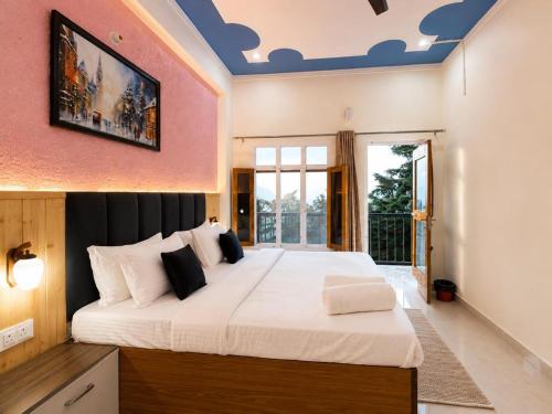 a bedroom with a large white bed with a painting on the wall at Anamika Forest View 1RK Near Kempty Falls Mussoorie in Mussoorie