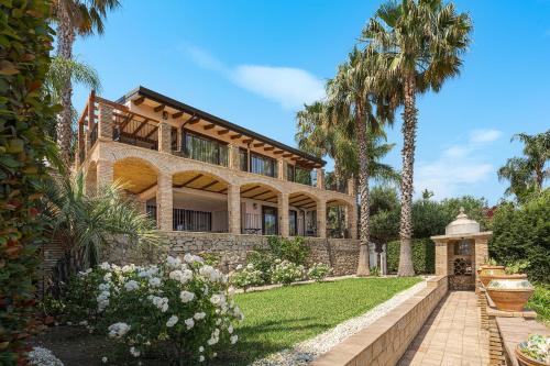 a large house with palm trees and a yard at Buena Vista in Letojanni