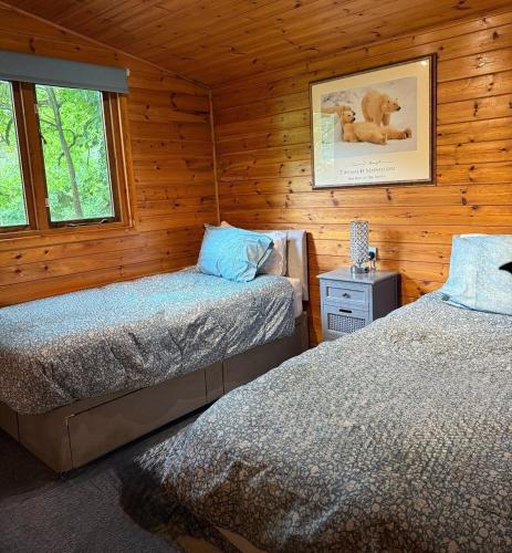 a bedroom with two beds in a wooden cabin at The Cabin at The Oaks in Fordingbridge