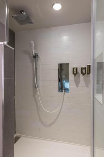 a shower with a hose in a bathroom at Hôtel & Suites Normandin Québec in Quebec City