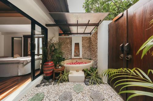a bathroom with a tub in a room with plants at Bandara Spa Resort & Pool Villas, Samui in Bophut