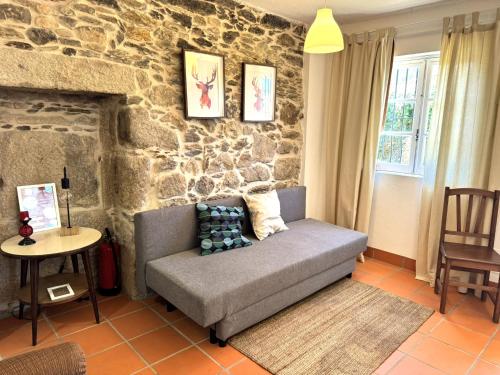 a living room with a couch and a stone wall at Casas da Loureira in Gondarém