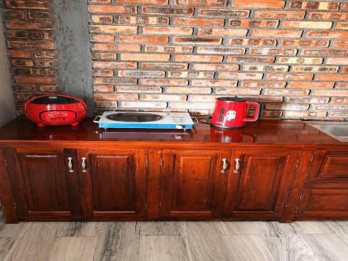 a wooden cabinet with two red cups and a brick wall at Củi Homestay Huế in Hue