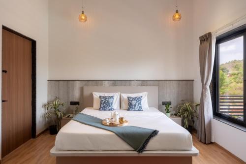 a bedroom with a large bed and a window at Saffronstays Crimson Crest in Khopoli