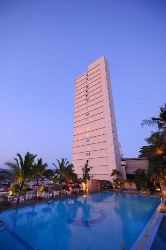 a hotel with a large swimming pool in front of a building at Grand Mandarin Betong Hotel in Betong