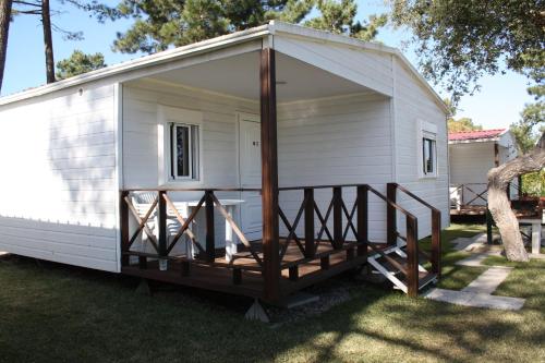 a small white shed with a porch on the grass at Valbom by Campigir in Sesimbra
