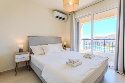 a bedroom with a bed and a large window at Resitour - Aphrodite Beachfront in Pírgos Psilonérou