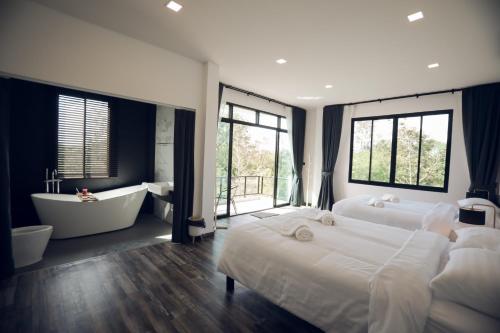 a large bedroom with two beds and a bathtub and a tubibliography at Issara Private Pool Villa Khaoyai in Pak Chong