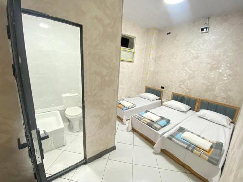 a bathroom with two beds and a glass door at Shinam hostel 777 in Chilanzar