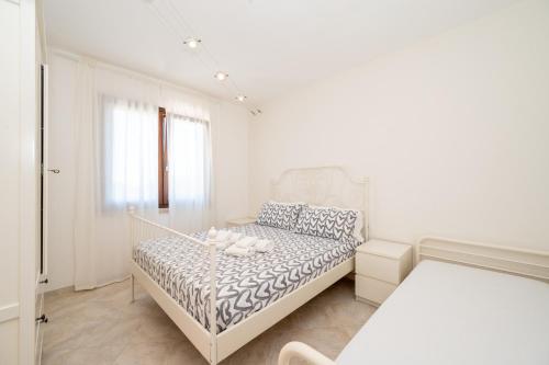 a white bedroom with a bed and a window at A 104 Puntavilla in La Maddalena