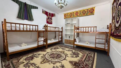 a room with two bunk beds and a rug at Gulzar Village Guesthouse in Dushanbe