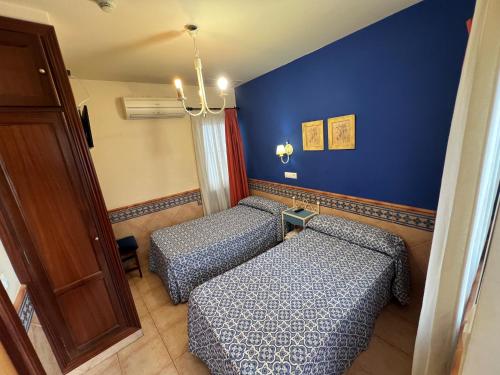 two beds in a room with blue walls at Pension Doña Trinidad in Seville