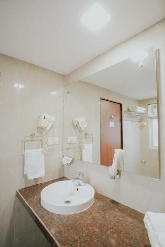 a bathroom with a sink and a large mirror at Hotel Phoenix Koregaon Park in Pune