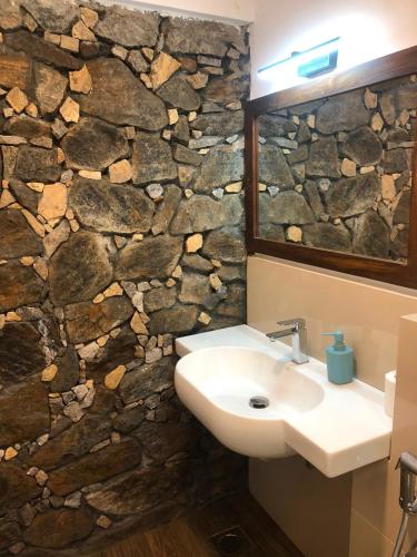 a bathroom with a sink and a stone wall at Kithulgala Cabana Resort in Kitulgala