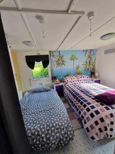 two beds in a room with palm trees on the wall at Airport Cottage in Aldergrove