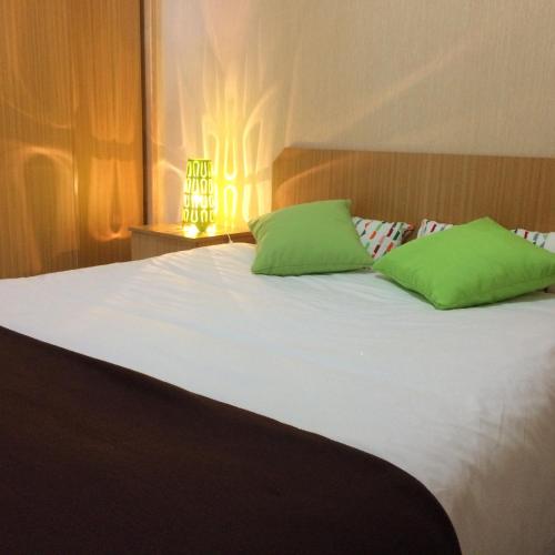 a large white bed with green pillows on it at Valbom by Campigir in Sesimbra