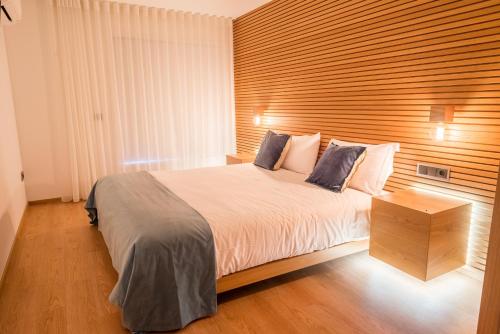 a bedroom with a large bed and a wooden wall at Almada Domus in Porto