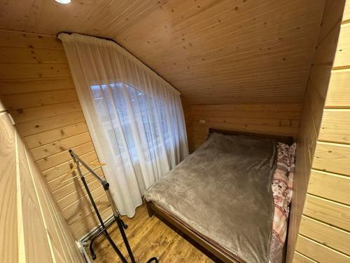 a small bed in a wooden room with a window at Андріана in Mykulychyn