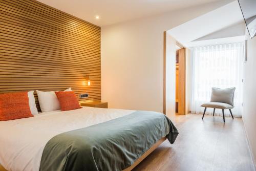 a bedroom with a large bed and a chair at Almada Domus in Porto