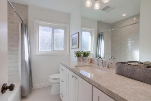 a white bathroom with a sink and a toilet at Beautiful Remodel 3 Bedroom 2 bathroom Home with Pool & Jacuzzi in Fullerton