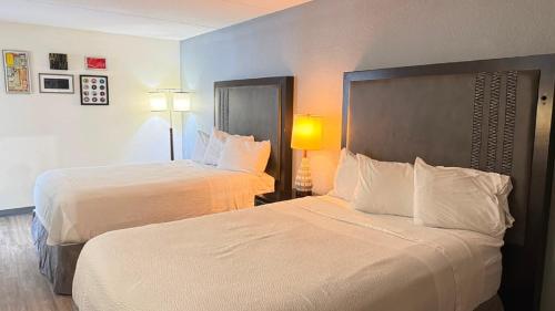 a hotel room with two beds with white sheets at Horizon Inn Norcross in Norcross
