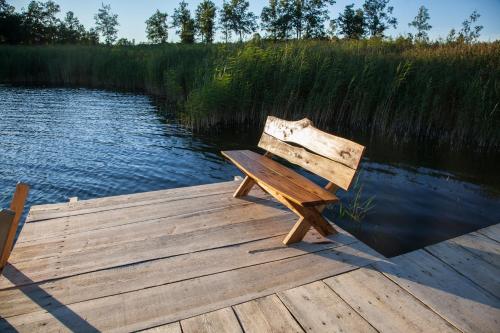 a wooden bench sitting on a dock next to a body of water at Siedlisko Wigry in Rosochaty Róg