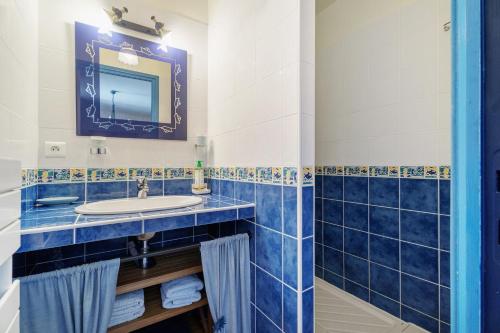 a blue tiled bathroom with a sink and a mirror at L'aoûtienne - 300m de la plage in Saint-Coulomb