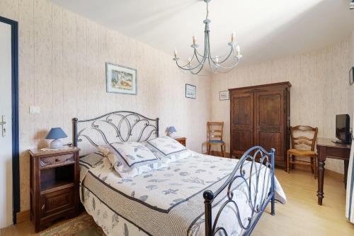 a bedroom with a bed and a chandelier at L'aoûtienne - 300m de la plage in Saint-Coulomb
